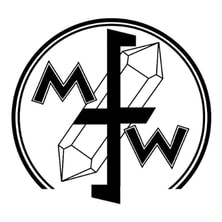 A black and white logo for the Midwest Federation of Mineralogical and Geological Societies. It features a black and white sketch of a doubly terminated crystal in the center. Centered over the crystal are the letters M F W. The crystal and letters are surrounded by a black circle outline.